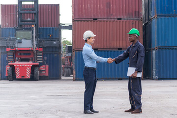 African American Environment engineer and young businessman holding hands with teamwork working togetter with Shipping container stacker background in commercial transport port