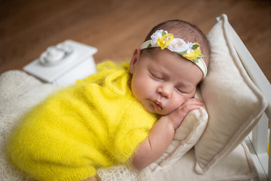 Girl newborn, yellow suit and headband with flowers,  close up