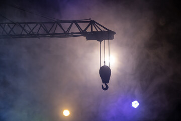Abstract Industrial background with construction crane silhouette over amazing night sky with fog and backlight. Tower crane against the foggy sky at night. © zef art
