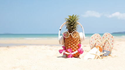 Summer party. Pineapple wearing sunglasses and listen to music with sunblock and sandal on beach and blue sky background. Tropical fashion. Summer Fashion on holiday concept