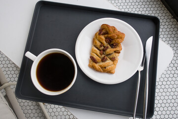pecan pie on a white plate with cup of coffee.