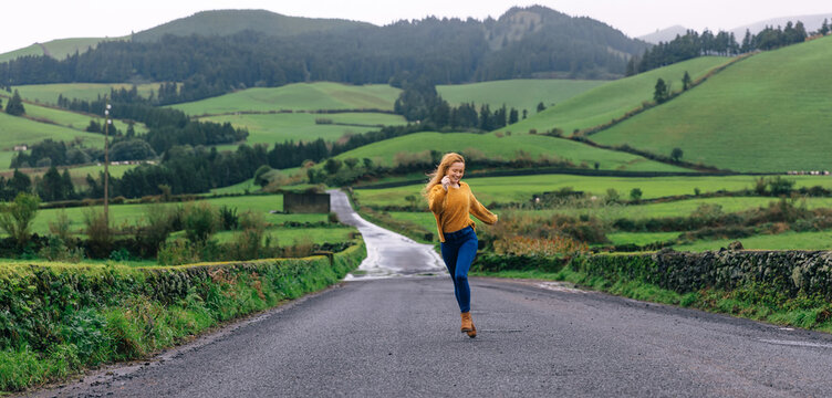 A Tourist Woman Walking Alone In The Middle Of The Road, Running To Have Fun, In The Vicinity Of A Beautiful Landscape.