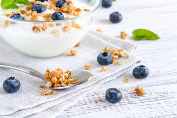 Natural greek yogurt and spoon with sprinkled muesli and blueberries on napkin