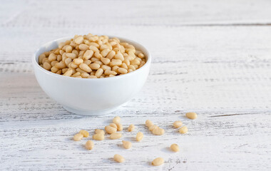Delicious pine nuts in a white bowl on wooden table