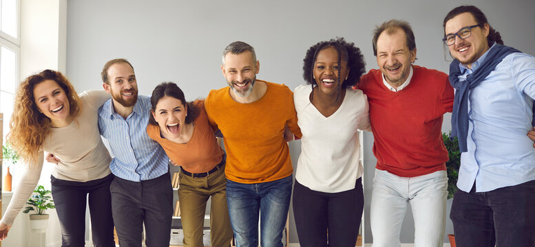 Team of happy diverse business colleagues and friends having fun together. Group portrait of excited people standing in row, huddling, laughing and looking at camera. Support and union concept, banner