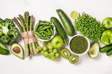 Green vegetables and fruits, greens and legumes on a white background.