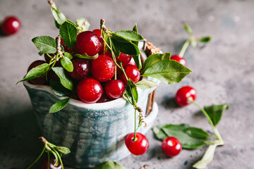 Fresh cherries with leaves and water droplets in a ceramic cup.