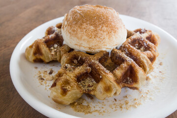A baked croissant dough in waffle iron with a scoop of vanilla ice cream.