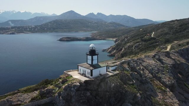Aerial view of La Revellata lighthouse above the Mediterranean sea near Calvi in the Balagne region of Corsica with snow capped mountains in the distance