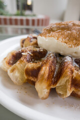 A baked croissant dough in waffle iron with a scoop of vanilla ice cream.
