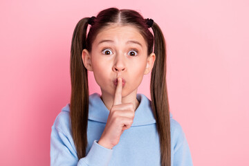 Photo portrait of small schoolgirl put finger near lips staring keeping secret isolated on pastel...