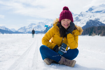 Fototapeta na wymiar Winter holiday trip to snow valley - young happy and excited Asian Chinese woman playful on frozen lake in snowy mountains at Swiss Alps enjoying unique landscape