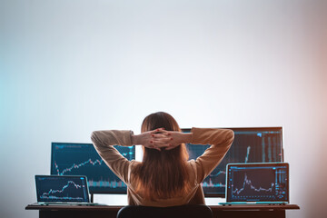 back view of female crypto trader resting and looking at monitor stock exchange