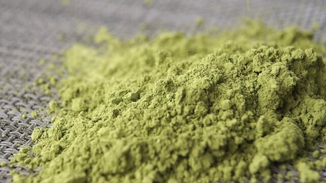 Pure Japanese matcha tea powder falls into a heap in slow motion. Macro shooting