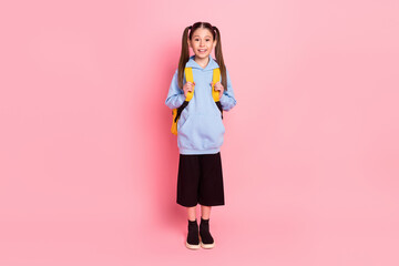 Full length body size view of attractive cheerful preteen girl going to school isolated over pink...