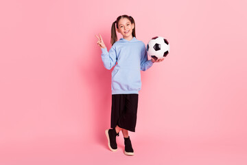 Full length body size photo of schoolgirl in sport outfit keeping ball showing v-sign gesture...
