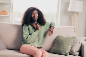 Portrait of attractive dreamy girl staying home sitting on divan watching tv show in flat house...
