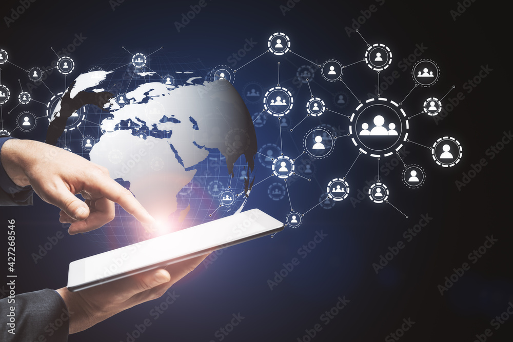 Aufkleber Hand with a tablet holding and touching the globe icon with muptiple small application icons near it on a dark background. Worldwide web and social interaction concept
