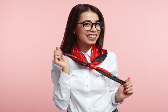 Attractive girl with eyeglasses, wearing white shirt and holding with her red scarf and smiling