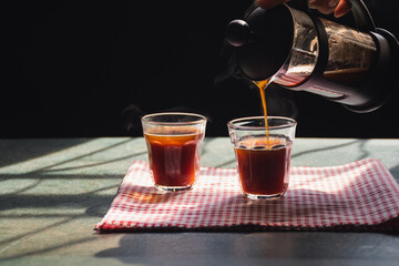 Aromatic coffees with hot smoke are poured into couple cup from French press coffee maker, Hot drink is good for health,On old wood table,Black background,Natural light,Selective focus,Healthy Eating.