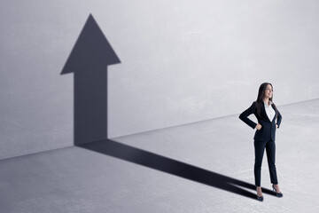 Success concept with happy businesswoman and black growing arrow as her shadow on concrete wall background