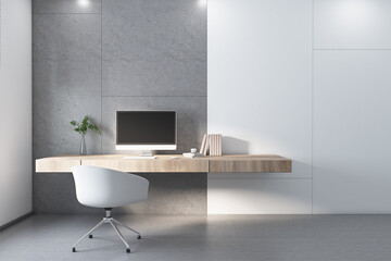 Modern home office workplace with concrete and white wall blocks, white chair, wooden table and computer monitor