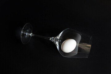 white chicken egg on a black background in a wine glass. wine glass on a black background. egg in a wine glass. protein. diet. proper nutrition. one egg. bad habits