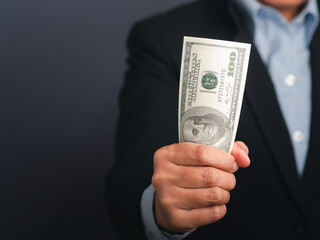 Businessman hand holding of US banknotes while standing in a studio. Close-up photo. Business and finance concept