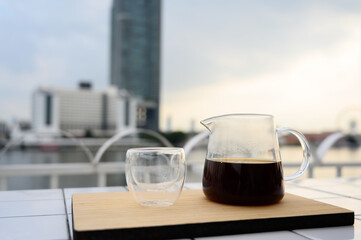 Drip freshly brewed coffee in glass jar with a cup on wooden tray. Hot brew coffee drink is good for health, Natural light. copy space.