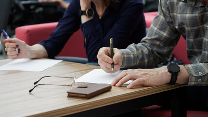 Adult man and woman fill out paperwork or forms. The concept of divorce proceedings, signing a...