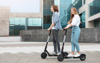 Young guy and lady having ride on electric kick scooter