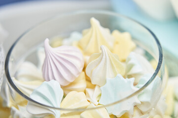 meringues of pale yellow, blue and lilac in a transparent vase