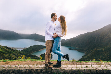 Naklejka premium crater lake surrounded by dense pine forest and aquatic plants on the shore two travelers hug on the landscape.