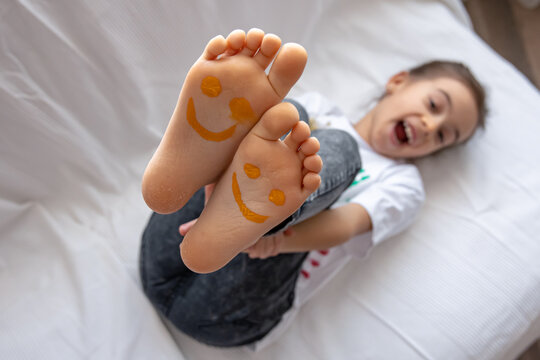 Close up of little girl's feet painted with smiles.