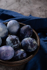 eggs are painted with blueberries in the form of a marble pattern. blue Easter eggs lie in a clay bowl on a stone background.