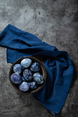 eggs are painted with blueberries in the form of a marble pattern. blue Easter eggs lie in a clay bowl on a stone background.