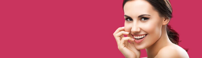 Portrait of beautiful young woman with naked shoulders, against red color background, with copy space area, for some text or slogan. Brunette girl in studio picture.