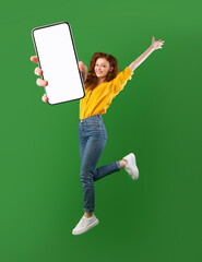 Hot offer, online sale. Carefree young woman jumping in air, showing cellphone with mockup space...