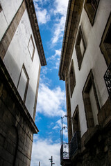 Fototapeta na wymiar Fachadas de piedra y cal enfrentadas en una calle estrecha con el cielo cortando la imagen por la mitad