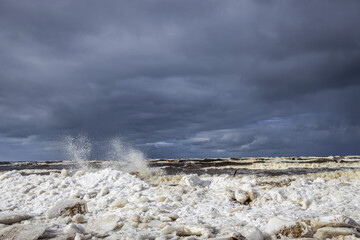 Winter coastal seascape with floating ice fragments on still cold water. Baltic Sea