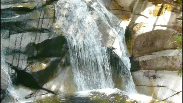 Wasserfall mit Sonnen und Schatten und felsigen Hintergrund