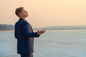 A young guy expresses emotions, on the seashore, sings and gestures. Against the backdrop of the sunset sea.