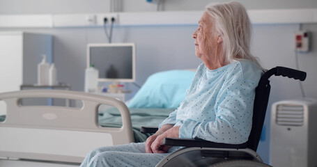 Senior sad woman sitting in wheelchair in hospital ward