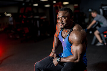 Fototapeta na wymiar Strong african man in a gym. Handsome man with big muscles, posing to the camera in a gym.