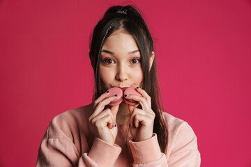 Asian brunette happy woman smiling while posing with macaroons