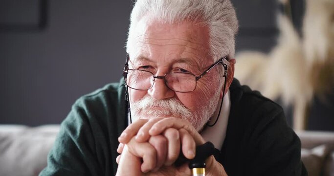 Worried Senior man holding his walking stick while sitting on bed at home