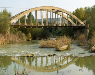 Un viejo puente de cemento se refleja en el rio
