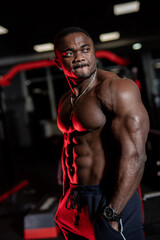 Fototapeta na wymiar African athlete in the gym. Muscular man showing muscles in gym, workout. Strong bodybuilding male