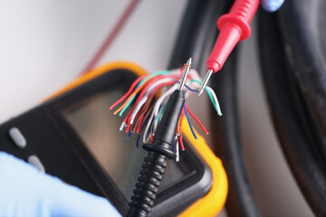 Two multimeter probes checking quality of network wiring closeup