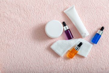 Serum oil moisturizing cream mask Cotton pads skin care cosmetics for home or salon beautician care. Cosmetics for skin cosmetology spa or daily use. Top View on pink towel with copy space